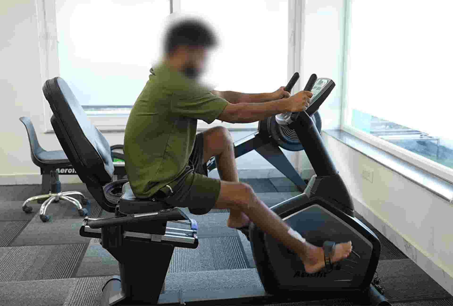 Patient performing strength training on a recumbent bike during orthopedic rehab
